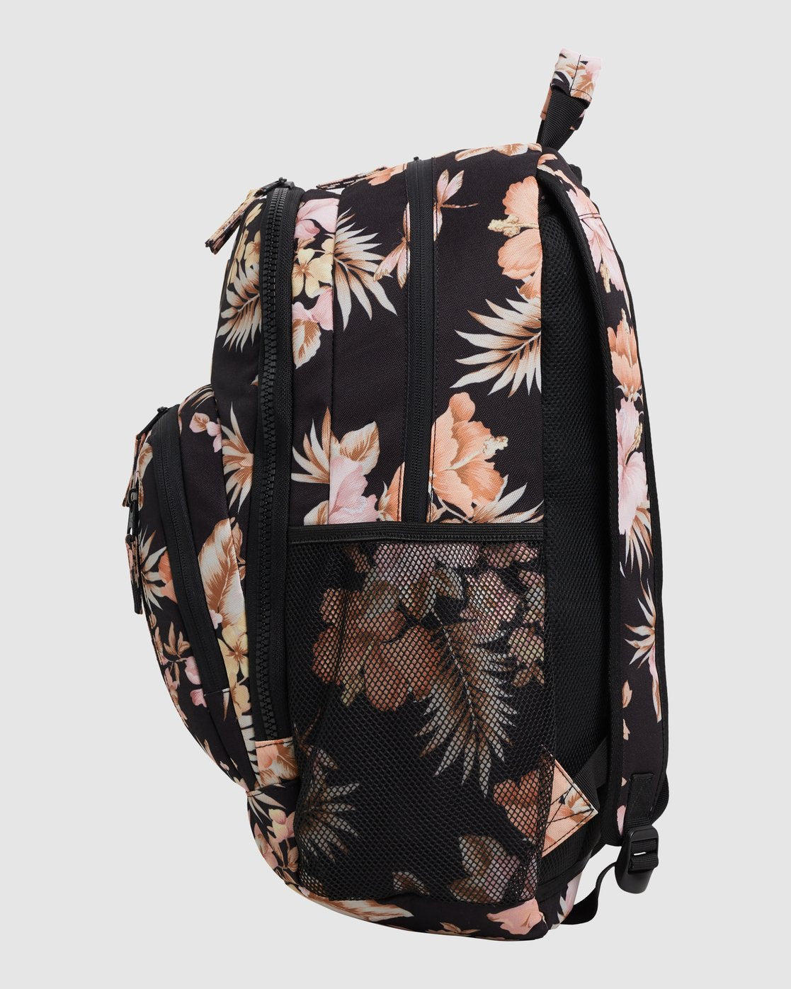 A black 31L Billabong Shallows Shaka Backpack with light pink and beige tropical floral patterns, multiple zippered compartments, and mesh side pockets is shown from the side against a plain light background.