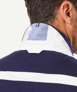 Close-up of a man from behind wearing the Gazman Classic Stripe Rugby, featuring a stylish navy blue and white striped design. The focus is on the back of his shoulders and neck, highlighting the shirt's collar, which is turned up, partially revealing a light blue inner lining.