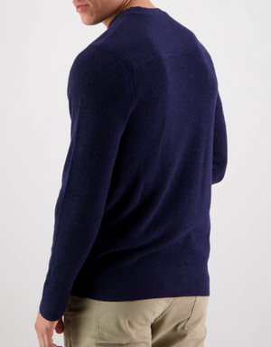 A person wearing a Swanndri Otahu River Crew Neck Merino Knit in dark blue and khaki pants is standing with their back to the camera against a plain white background.
