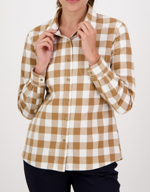 A person in black pants adjusts the collar of a Swanndri Womens Taranaki Tailor Shirt—beige and white checkered, long-sleeved, and 100% cotton with a tailored fit. The head is partly out of frame, set against a plain white background.