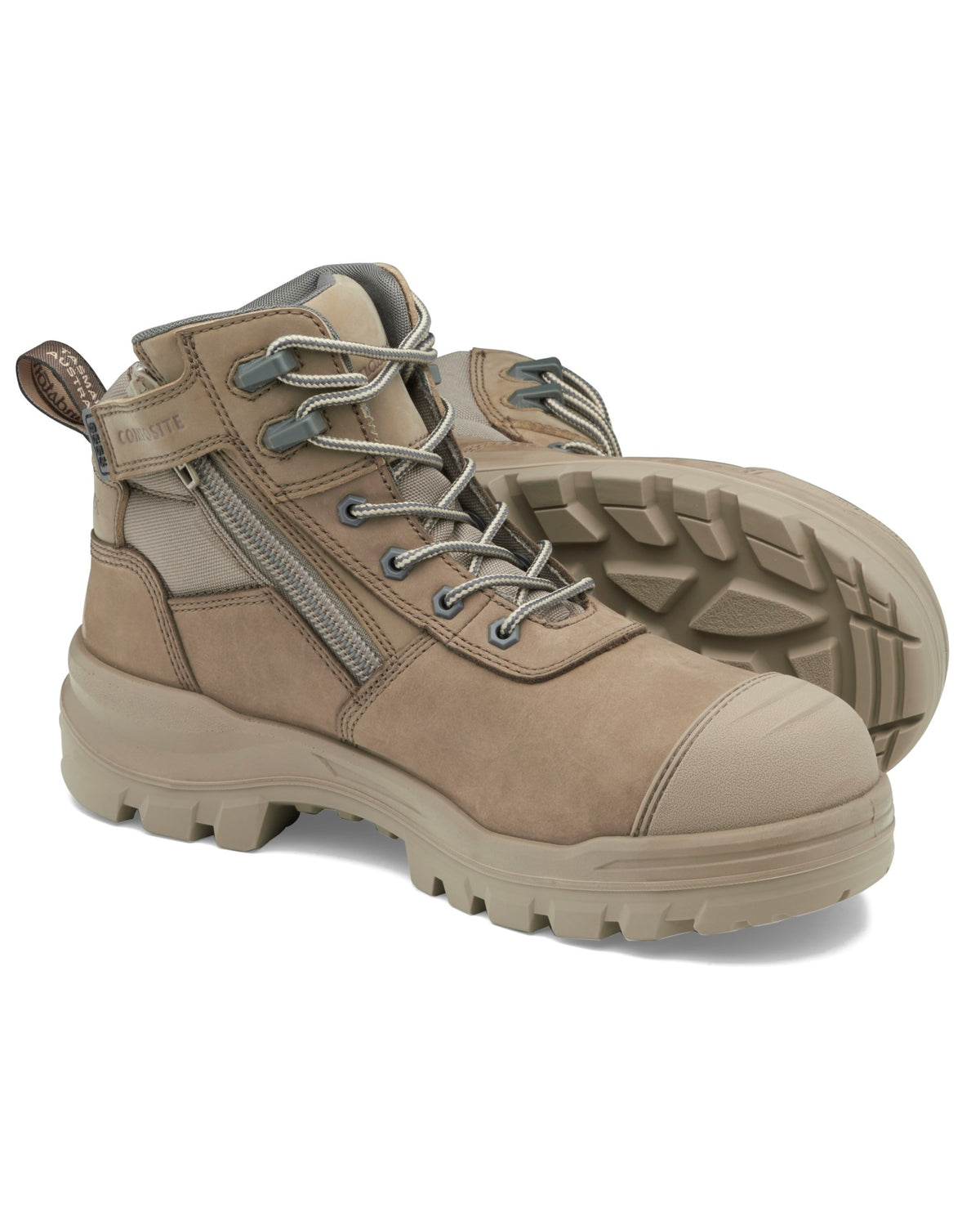 A pair of sturdy, tan-colored Blundstone RotoFlex 8553 Mid Zip Safety Boots with thick, textured INFINERGY® rubber soles. The safety boots feature grey laces, a side zipper, and reinforced toes. They are positioned with one boot upright and the other laying on its side, displaying both the side and the sole.