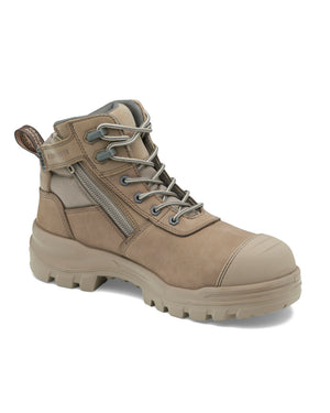 The image shows a tan-colored Blundstone RotoFlex 8553 Mid Zip Safety Boot with thick, durable soles and INFINERGY® technology. The safety boot features a combination of laces and a side zipper for ease of wear. The design includes reinforced toe and heel areas, offering additional protection.