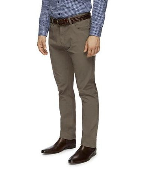 A person dressed in a blue patterned button-up shirt, brown belt, stylish City Club Austin Road Pants, and dark brown dress shoes. The photo is cropped to show only the slim fit torso and legs.