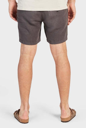 A person is shown from behind wearing a beige shirt, relaxed-fit Academy Brand Riviera Linen Shorts in gray with an elastic waist, and brown sandals, all set against a white background.