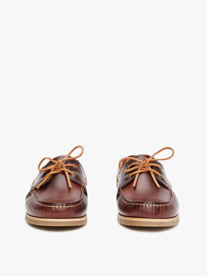 The RM Williams Hobart Boat Shoe features brown yearling leather moccasins with light tan laces, a flat rubber outsole, and detailed stitching, shown from the front against a plain white background.