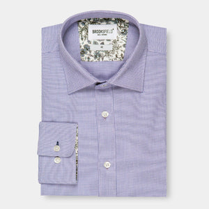A Brooksfield Micro Textured Shirt, neatly folded and featuring a light purple hue with long sleeves. This stylish shirt showcases a small check pattern along with delicate floral inner collar and cuff linings, all elegantly displayed against a white background.