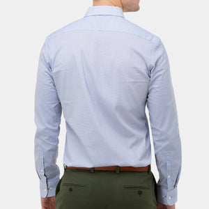 A person is shown from the back, wearing a light blue Brooksfield Stretch Print Shirt paired with green regular fit trousers. The shirt features a stiff point collar and buttoned cuffs, and it is tucked into the trousers. The person is also sporting a brown belt against a white background.