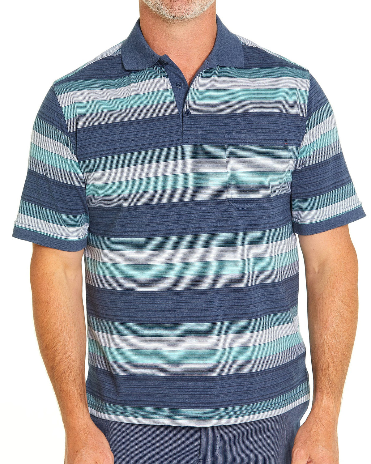 A man wearing a blue, green, and gray striped Breakaway Otto Kinnersly Jersey Polo stands against a white background. The shirt features a classic collar, a button placket, and a small pocket on the left chest. He is also wearing blue trousers. His head is cropped out of the image.