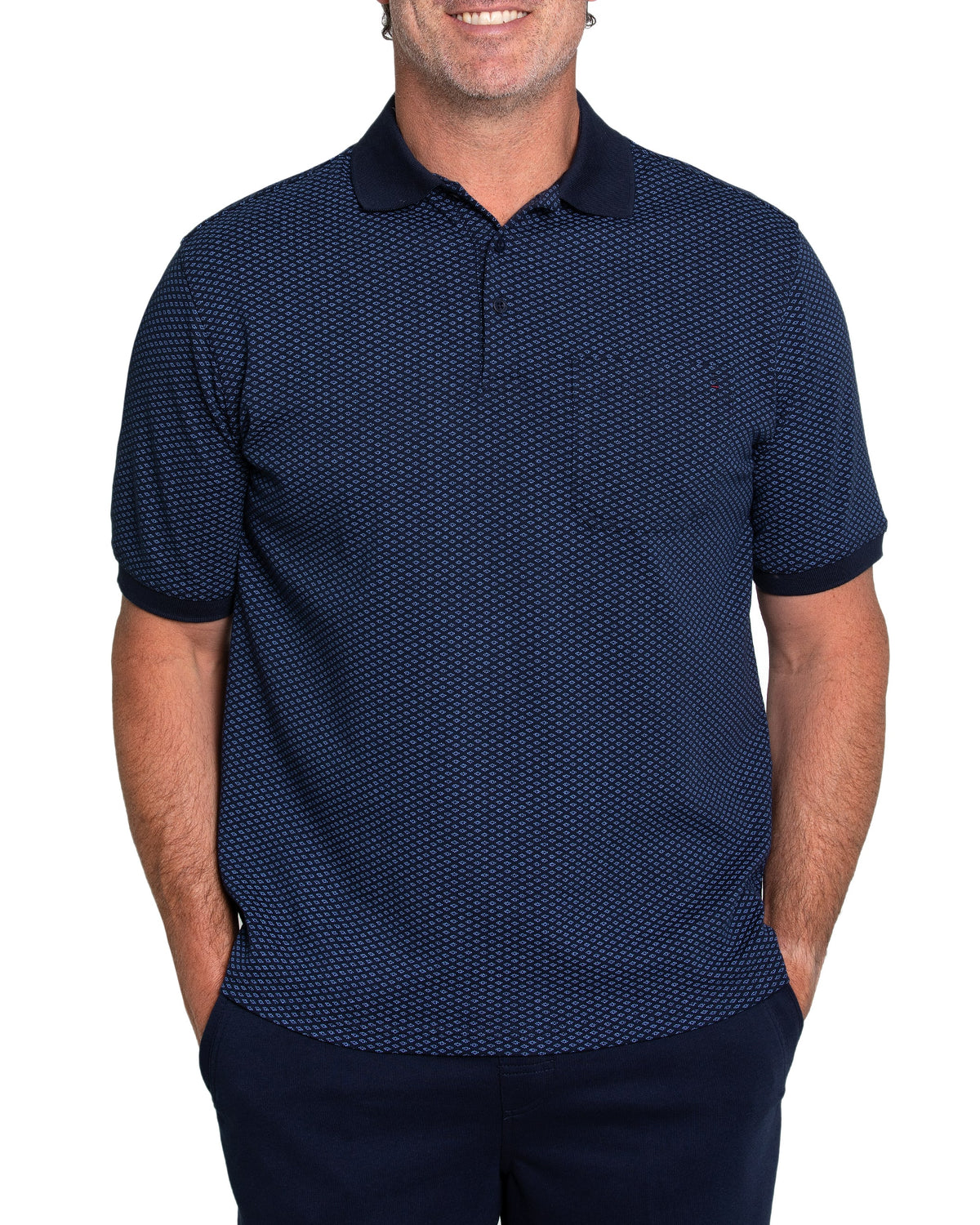A person stands with hands in pockets against a white background, wearing the Breakaway Diamond Micro Prima Polo, a navy blue casual shirt with a classic collar and dark blue sleeve cuffs, featuring a subtle small repeated design.