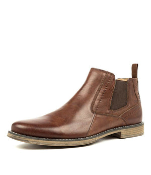 The Colorado Mills Boot is a sleek brown leather Chelsea boot featuring elastic side panels, a pull tab, a wooden textured sole, and light stitching detail. This elegant men's boot is ideal for both casual and formal occasions.