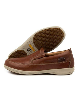 The Colorado Affleck Pull On Shoe features a brown leather design with white stitching, slip-resistant patterned rubber sole, and memory foam cushioning for comfort. One shoe is upright while the other showcases the grip design of the sole.