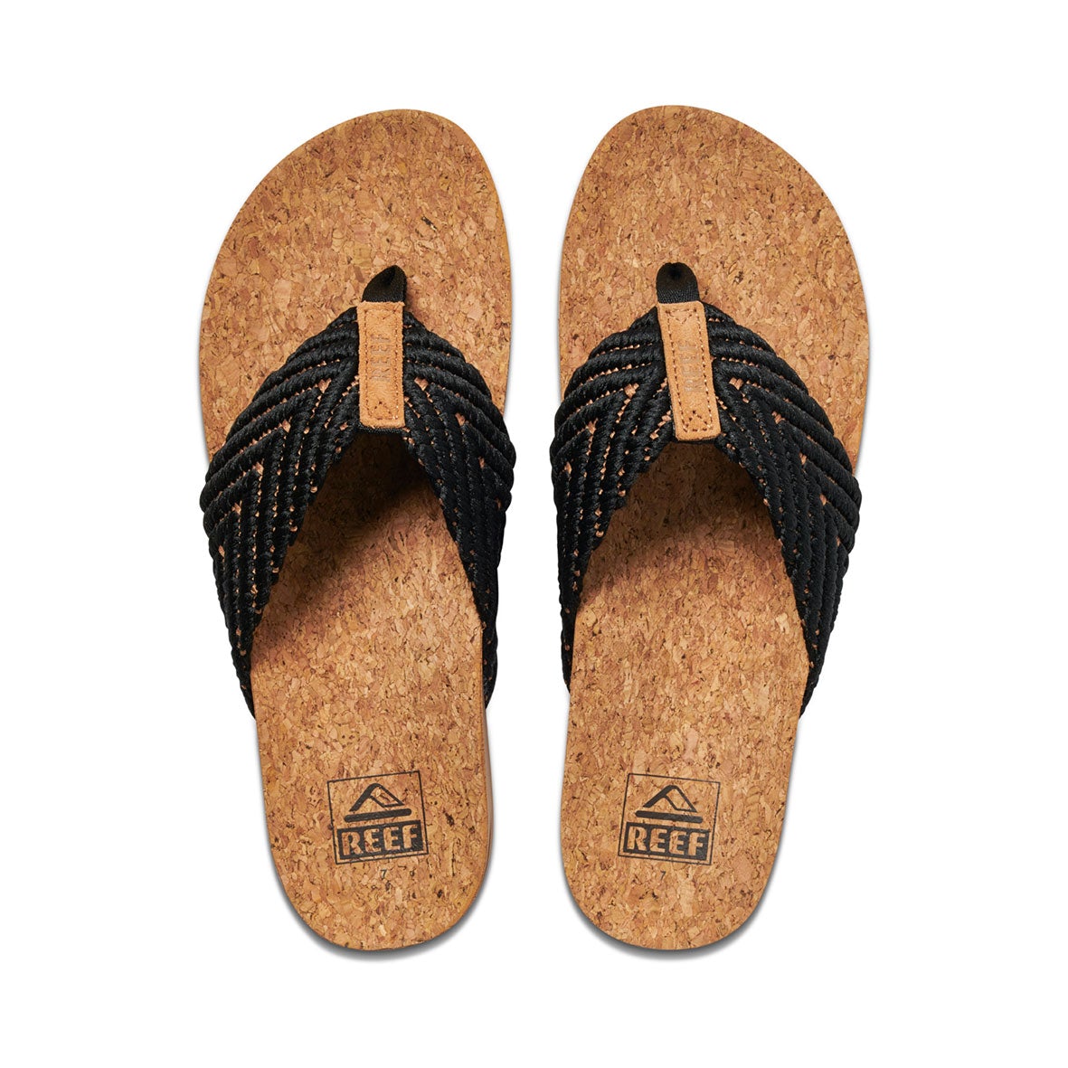 The REEF Cushion Strand sandals feature cork soles and black woven straps with a cushion bounce midsole for comfort. The footbed has a "Reef" logo and mountain design, while the straps include a toe loop with a tan accent.