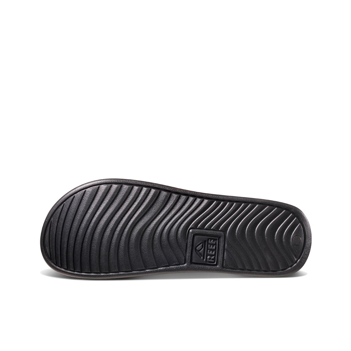 The image features the sole of a REEF One Slide sandal in black, showcasing wavy tread patterns and a prominently displayed brand logo, emphasizing its waterproof design.