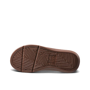 The image showcases the sole of a brown REEF Santa Ana LE sandal, featuring an intricate pattern of grooves and lines designed for traction. The brand name "Reef" is prominently imprinted centrally on the sole, signifying the footwear's manufacturer. Renowned for crafting water-friendly thongs, Reef guarantees durability and style in every step.