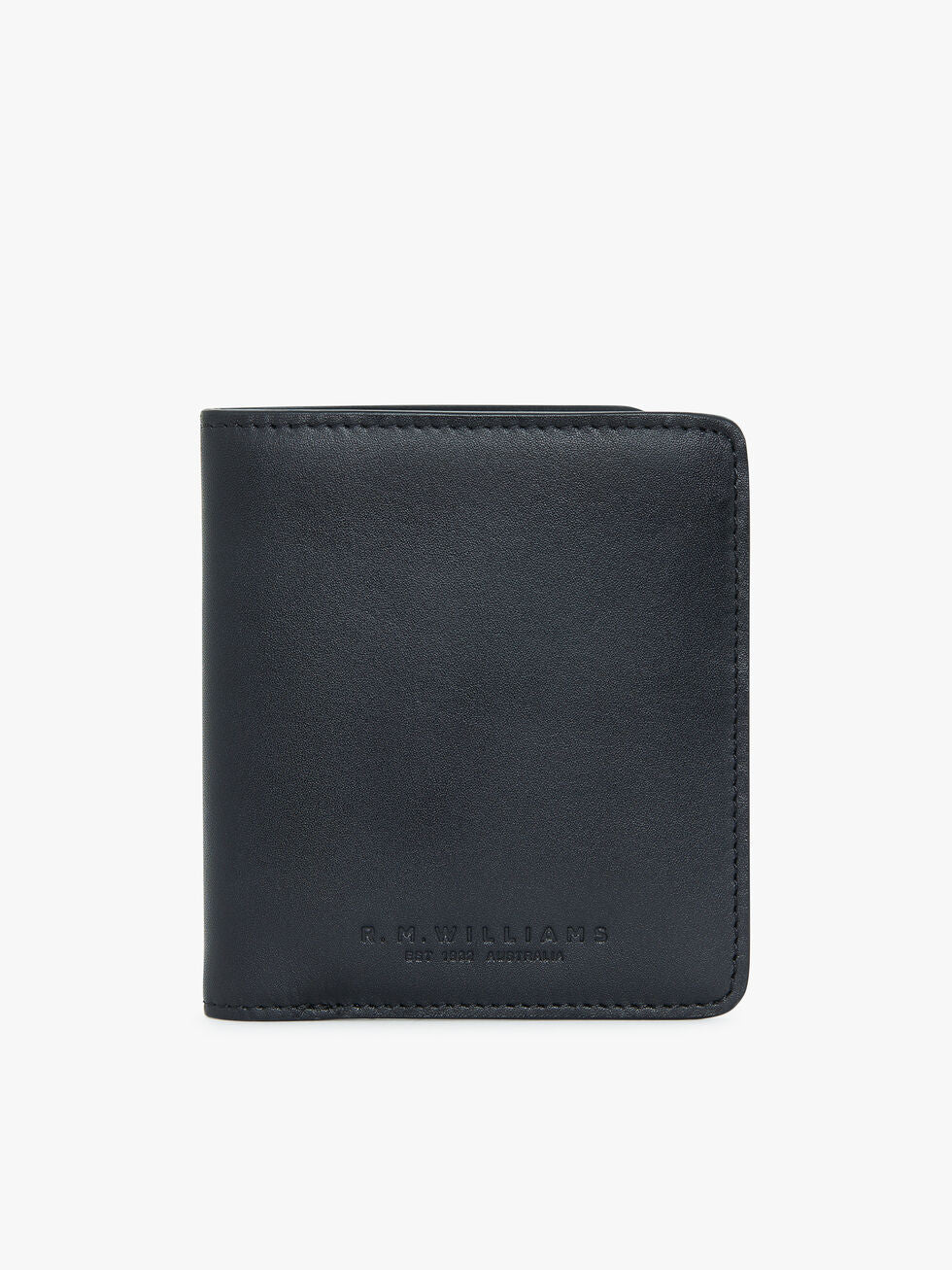 The RM Williams Urban Bi-Fold is a black, full-grain leather wallet with a simple and sleek design. It features an embossed inscription near the bottom on the front, reading "R.M. Williams" and "Est 1932 Australia" in small, capitalized letters. The wallet looks brand new and is showcased against a plain white background in the photograph.