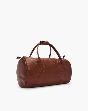 The RM Williams Leather Ute Bag is a brown, Australian Made cylindrical bag with two handles, zipper closure, visible stitching, and is shown on a white background.