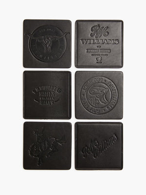 The RM Williams Heritage 6 Pack Coaster Set includes six square black leather coasters, each embossed with unique designs, logos, text, symbols, and images. Proudly Australian-made, they are arranged in two vertical rows of three.