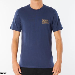 A person wearing the navy Rip Curl 50/50 Scratch Tee made of 100% cotton, featuring a small rectangular logo on the left chest area with the text "Rip Curl" and "The Search." The comfortable t-shirt is showcased as the person faces forward against a plain white background, with "NAVY" written in the bottom left corner.