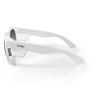 The SafeStyle Cruisers feature white, thick polycarbonate frames and tinted polarized lenses with UV400 protection. A cursive "Style Style" logo embellishes the side arms. Placed on a reflective surface, they create a mirrored effect.