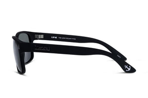 Matte black Liive The Lewy Polar Sunglasses placed on their side, showcasing the left arm of the frame. The arm is inscribed with "LIIVE" and "The Lewy Polar 24092" alongside an anchor symbol near the tip. These sunglasses have a sleek, lightweight polycarbonate design with dark, UV-protection lenses.