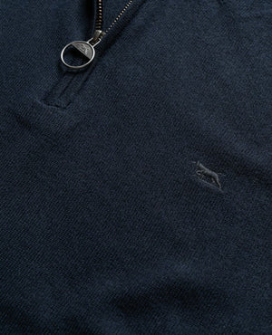 Close-up of a dark blue Rodd & Gunn Bishopsdale Knit with a metal zipper pull ring. The embroidered logo of a small abstract figure in a lighter shade of blue is visible on the lower right section of the Australian Merino quarter-zip knit. The fabric appears to be soft and textured.
