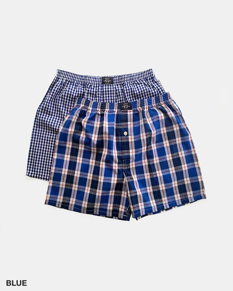 The Coast Clothing Woven Check Boxers 2 Pack is displayed against a plain white background, showcasing two pairs of blue plaid boxers. One pair, crafted from 100% cotton, features a smaller checkered pattern, while the other pair boasts a larger and more distinct plaid design. The word "BLUE" appears in the bottom-left corner of the image.