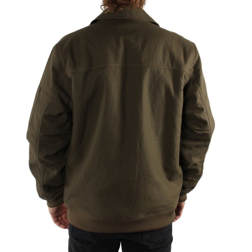 A person with long hair is seen from the back wearing a dark olive green Ringers Western Mildura Sherpa Bomber Jacket and black pants. This rugged, water-resistant jacket features sherpa lining and a collar, offering a loose fit that extends beyond the waistline. The background is plain white.