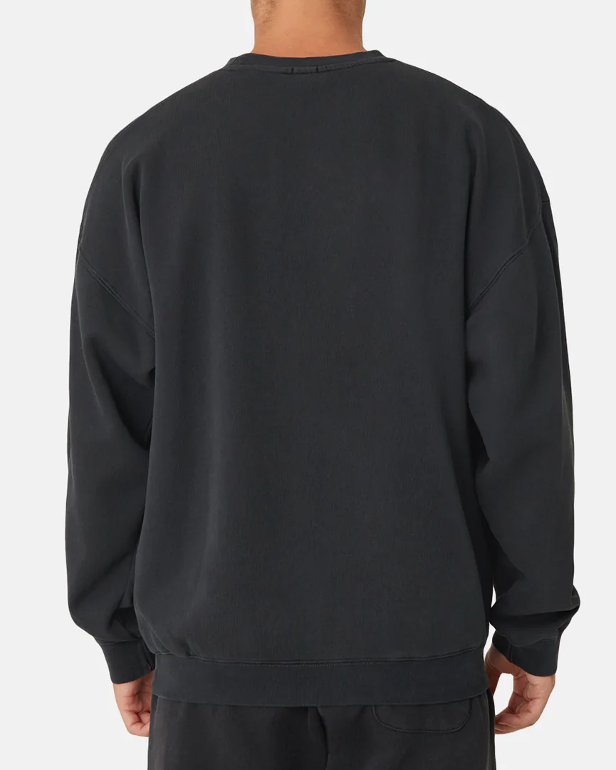 The person is wearing Industrie The Del Sur Sweat, a plain black, long-sleeved oversized jumper paired with matching pants, viewed from the back against a white background, exuding a relaxed and casual vibe.