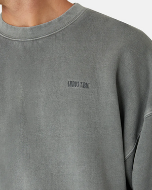 A close-up shows a person wearing "Industrie The Del Sur Sweat," a comfy faded gray sweatshirt with an oversized fit and the "INDUSTRIE" logo embroidered on the upper chest. Only part of their face is visible.