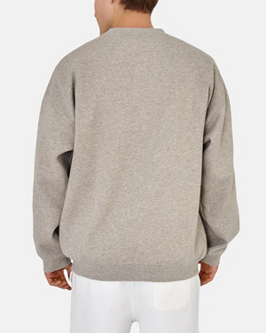 Someone faces away from the camera, wearing Industrie The Del Sur Sweat in an acid wash with an oversized fit and long sleeves. They're paired with white pants against a plain white background, highlighting the jumper's comfort.