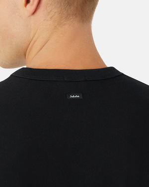 A person wears the Industrie The Del Sur Tee in an oversized black fit, shown from the back with focus on the neck area. A small black label is visible near the neckline on this comfortable shirt, against a plain white background.