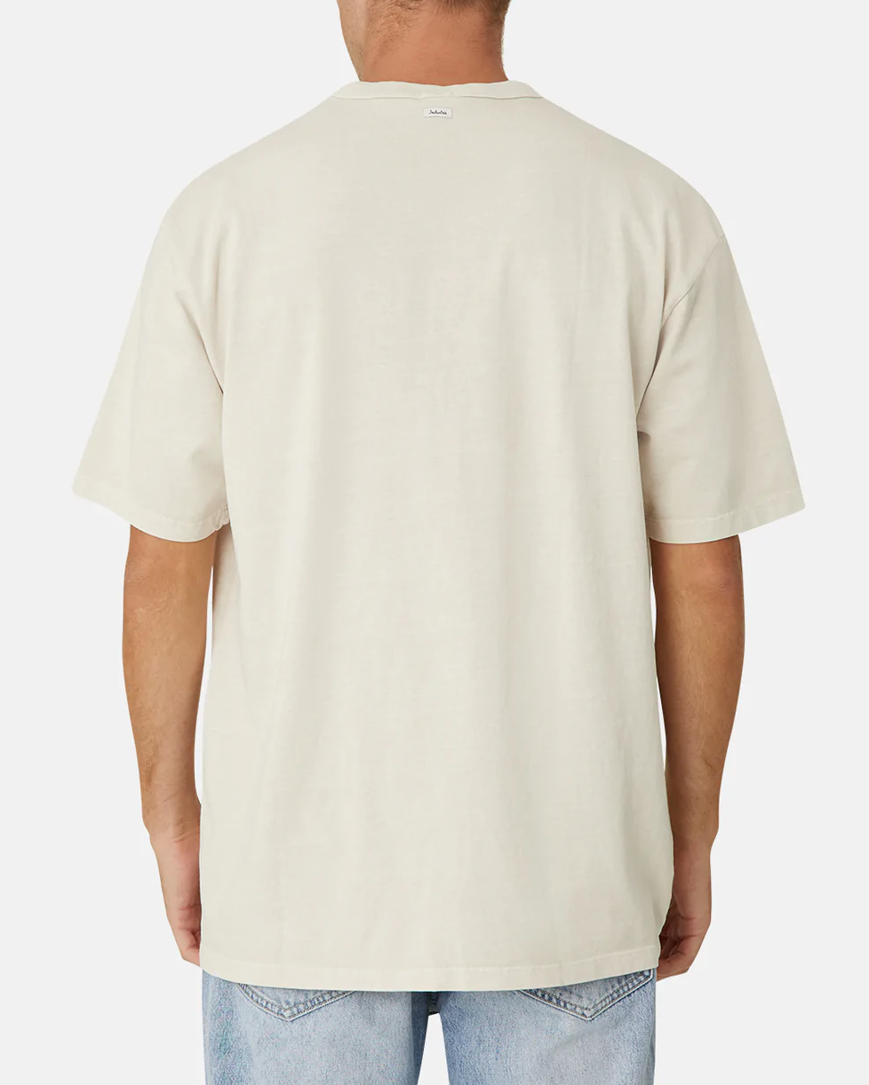 Rear view of a person wearing the oversized and comfortable Industrie The Del Sur Tee in beige, made from 100% cotton, paired with light blue jeans against a white background.