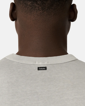 Close-up of the back of a person’s neck and shoulders, wearing the Industrie The Del Sur Tee in light gray with a small black "Indispensable" collar label. The relaxed, oversized fit stands out against a plain white background.