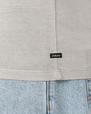 Close-up of a person wearing the Industrie The Del Sur Tee in light gray, made from 100% cotton, featuring a small black "Industrie" tag near the hem. It's paired with light blue denim jeans for an effortlessly stylish look.