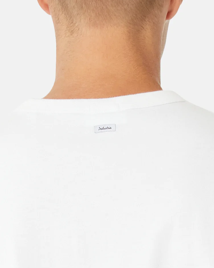 Back view of a person in an oversized fit white Industrie The Del Sur Tee. A small white label with "Indulite" is visible below the neckline. Made from 100% cotton, the shirt blends seamlessly into the plain white background.