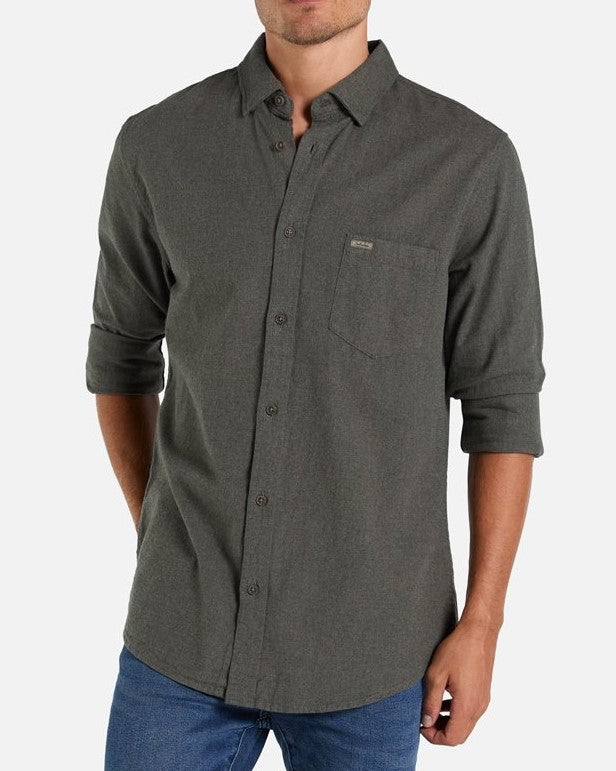 A man wearing the Industrie The Taylor Shirt in dark gray, made from 100% cotton with a breast pocket and rolled-up sleeves, paired with blue jeans. He is standing against a plain white background.