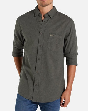 A man wearing the Industrie The Taylor Shirt in dark gray, made from 100% cotton with a breast pocket and rolled-up sleeves, paired with blue jeans. He is standing against a plain white background.