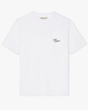 The RM Williams Longhorn Byron Tee is a plain white T-shirt made from premium cotton jersey, adorned with a small "R.M. Williams" logo in black cursive text on the left side of the chest. This shirt features a crew neck and short sleeves, making it an ideal unisex style.