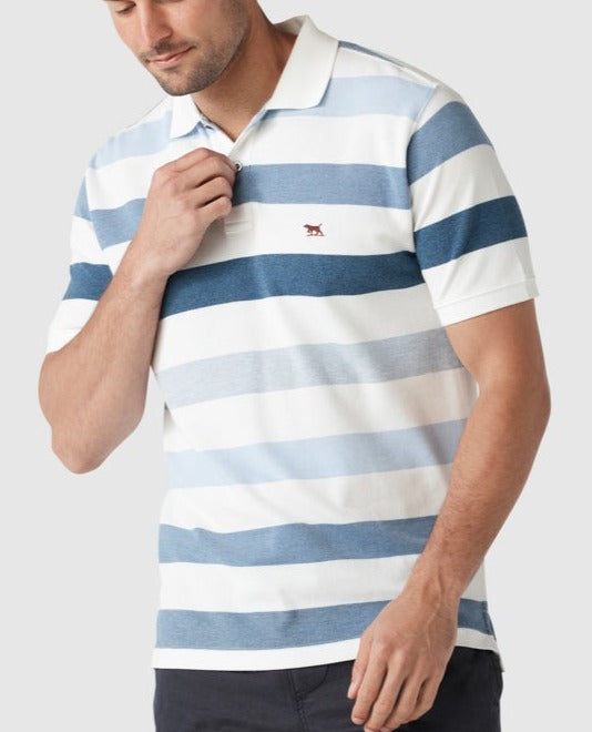 A man adjusts a button on his Rodd & Gunn Mount Benger Polo, which is 100% cotton with light and dark blue horizontal stripes and an embroidered chest logo. He pairs the short-sleeved shirt with dark pants against a plain light background.