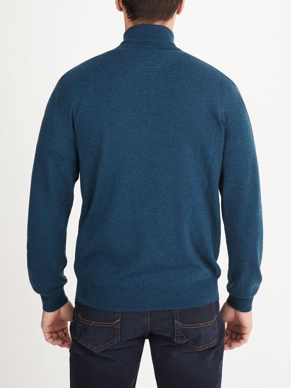A person wearing the RM Williams Ernest Sweater—a blue wool, quarter-zip sweater—and dark jeans stands facing away from the camera against a plain white background.