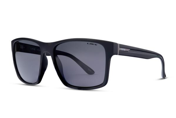 A pair of Liive Kerrbox Polar Sunglasses, with black square frames and dark grey lenses, lays on a white background. The modern and sleek design showcases subtle branding on the arms and lens while providing excellent UV protection.