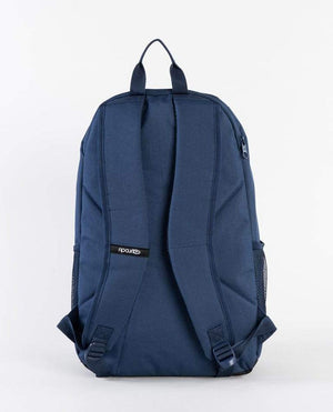 A dark blue Rip Curl Ozone 30L Backpack with adjustable padded shoulder straps and a small black tag with white branding. It features mesh side pockets, an insulated cooler compartment, and a top handle for easy carrying. The background is plain white.
