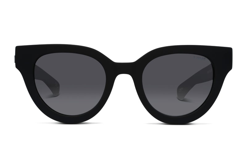 The Liive Rumble Polar Sunglasses feature a pair of black cat-eye lenses with dark tinting. The polycarbonate frames boast sharp, angular edges that curve slightly upward at the outer corners. These sunglasses provide UV protection while offering a stylish and modern appearance.