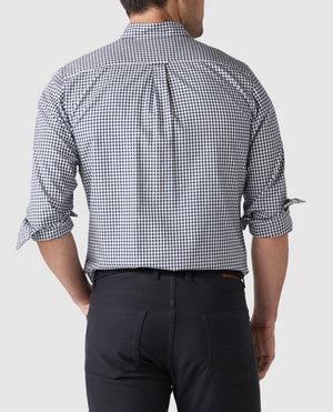 A man is seen from behind wearing a stylish Rodd & Gunn Gunn Check Oxford Sports Fit Shirt, featuring a black and white checkered pattern. The 100% cotton shirt has rolled-up sleeves. He pairs it with dark pants against a plain white background.