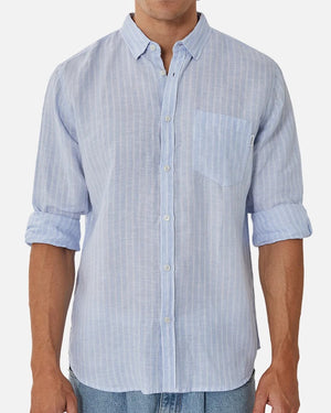 A stylish person wears the Industrie The Mattera Long Sleeve Shirt in light blue with vertical stripes. The linen shirt has a chest pocket and rolled-up sleeves, complementing the plain white background.