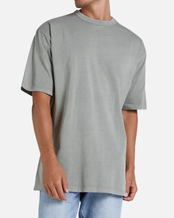 A person in the oversized Industrie The Del Sur Tee and light blue acid wash jeans stands against a plain white background, facing forward with one arm slightly bent at the elbow, highlighting the outfit's casual vibe.