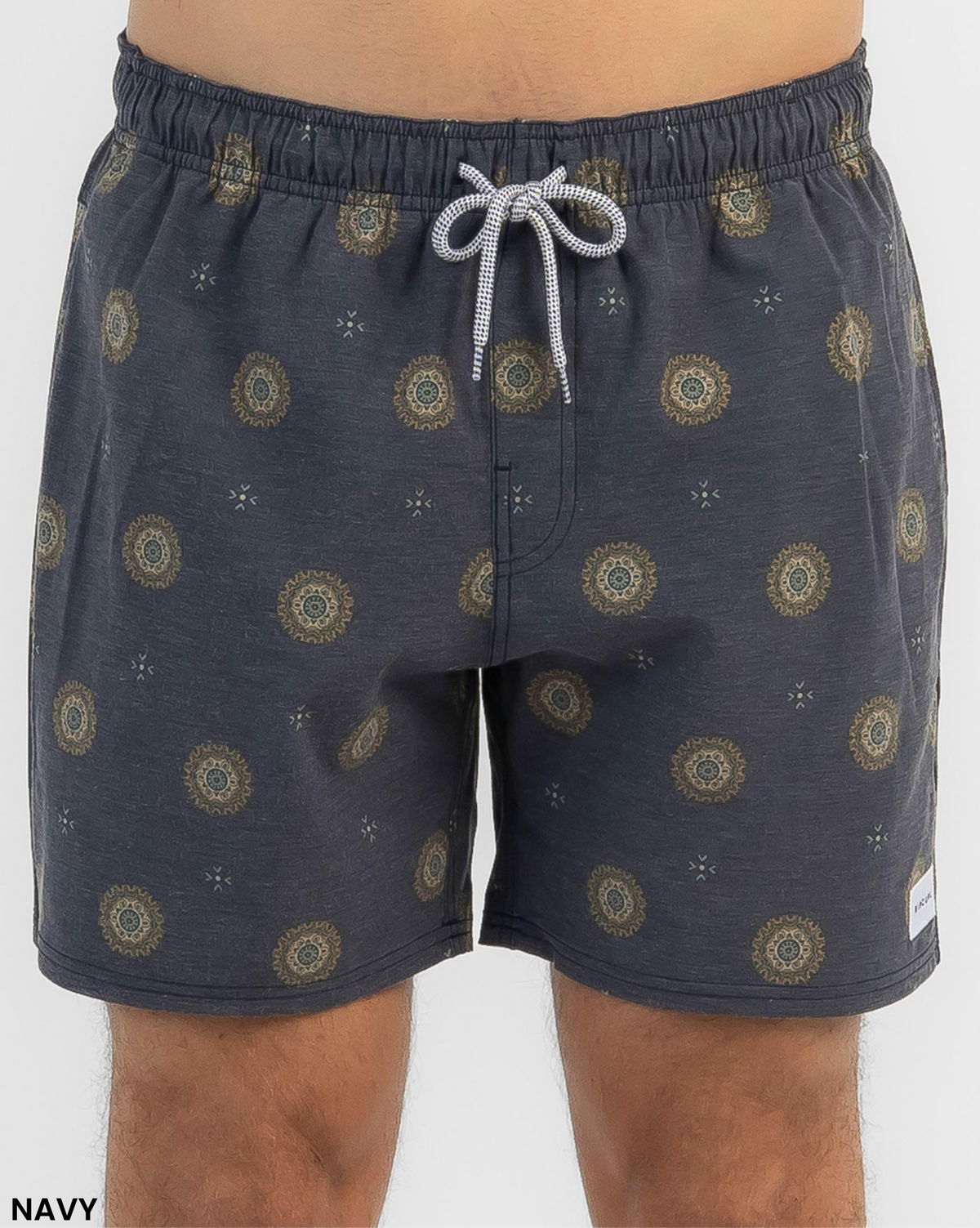 A person wearing Rip Curl Party Pack Volley Shorts in navy blue with a small yellow and teal circular pattern, white and gray drawstring, elastic waist, and a small white patch on the lower left leg.
