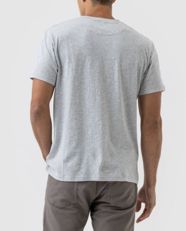 A person stands relaxed in a Rodd & Gunn Logo T-Shirt and gray pants, crafted from premium Australian Cotton, exemplifying comfort and style against a light backdrop.