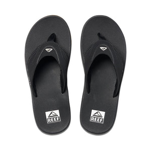 The REEF Fanning flip-flops are black with textured soles and feature a stylized wave logo on the synthetic strap. The brand name "REEF" is prominently displayed on the heel, and they include an EVA footbed for added comfort.