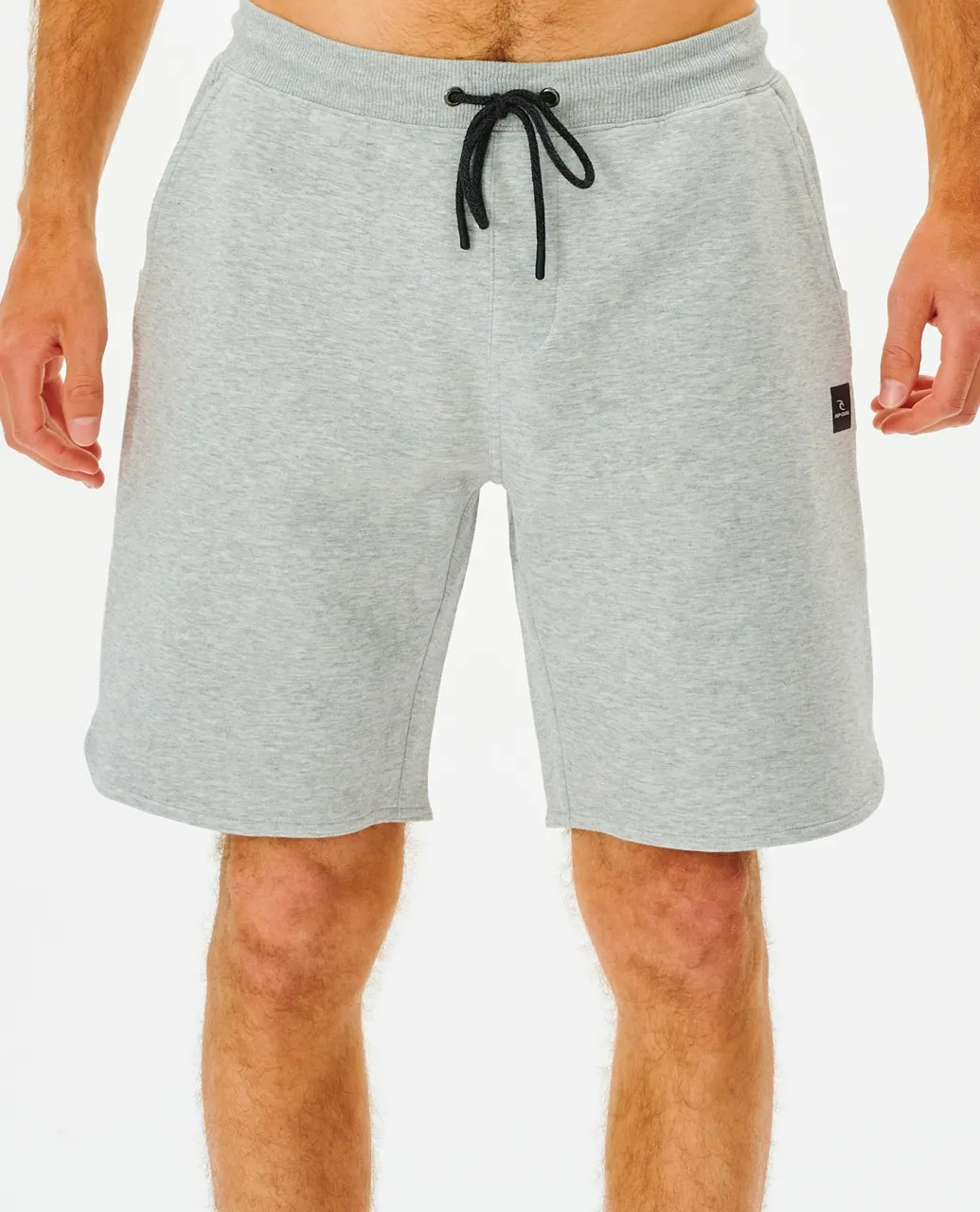 A person wears light gray Rip Curl Vaporcool Short with a black drawstring and small black logo on the left pocket. These comfortable knee-length shorts are against a plain white background.